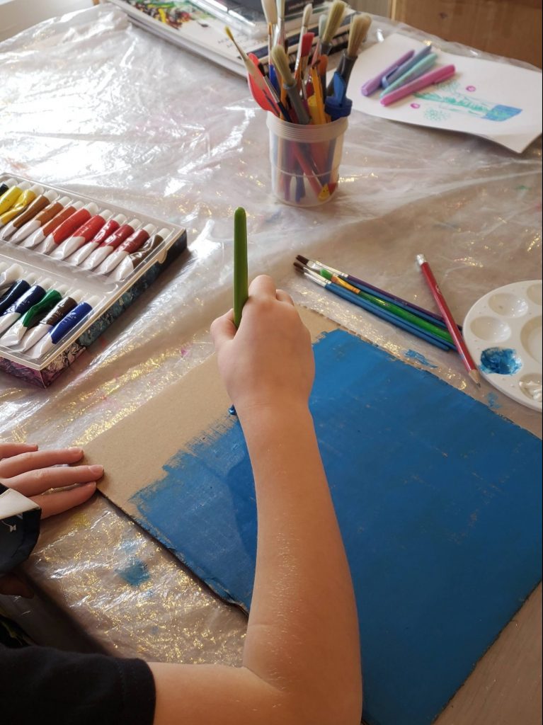 Painting a piece of recycled cardboard blue to represent the Great barrier Reef seabed