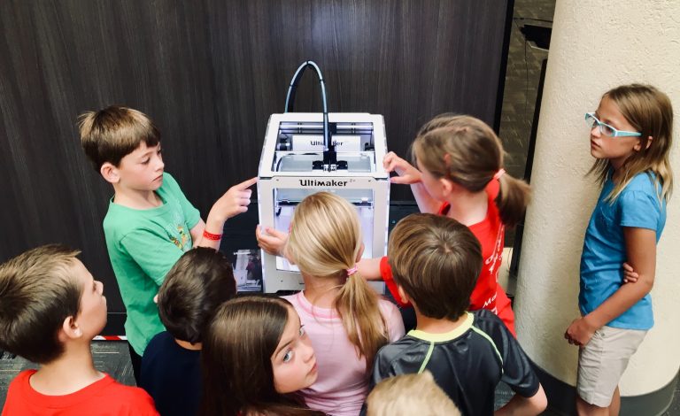 Kids gather around a 3D printer to learn and create