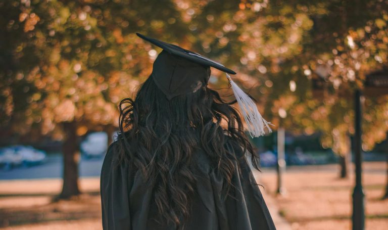 Woman in Black Long Sleeve Dress Standing on Brown Concrete Pathway